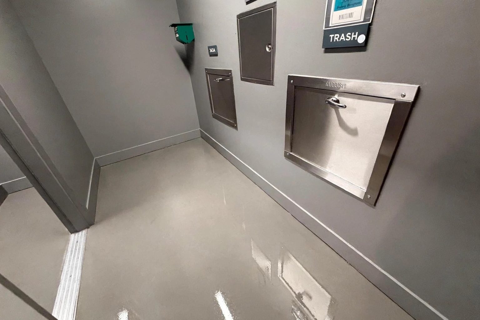Clean, well-lit trash chute room in a modern apartment building